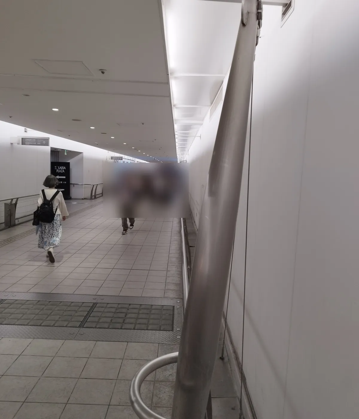 The same kind of pylons and cables repeat down the length of the passage. People walking in the passage have been blurred so they cannot be identified